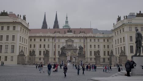Tourists-walking-in-front-of-the-historical-Prague-Castle-with-sculptures-and-spires
