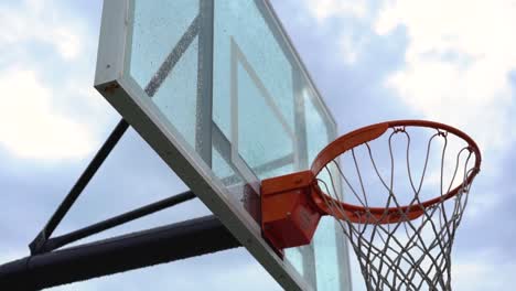 Looking-up-at-urban-sports-basketball-backboard-and-hoop-against-cloudy-overcast-sky