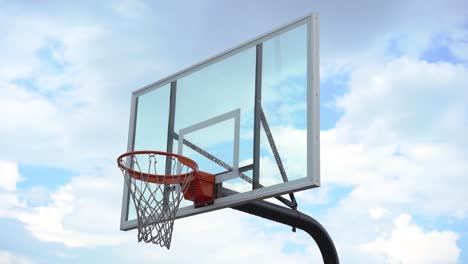 Panning-across-playground-basketball-backboard-and-hoop-with-cloudy-overcast-sky-background