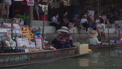 Vorwärtsbewegung,-Seitenansicht,-Malerischer-Blick-Auf-Den-Schwimmenden-Markt-In-Thailand,-Menschen,-Die-Auf-Den-Stufen-Im-Hintergrund-Sitzen