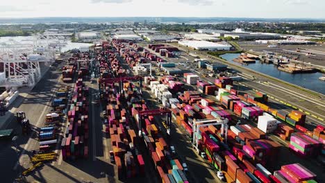 Industrial-vehicles-moving-and-sorting-shipping-containers-at-busy-shipping-port-near-New-York-City---right-to-left-sideways-pan-aerial-footage