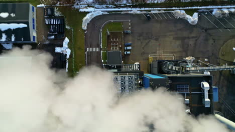 Top-down-drone-shot-descending-above-air-vent-at-a-smoking-factory,-winter-day