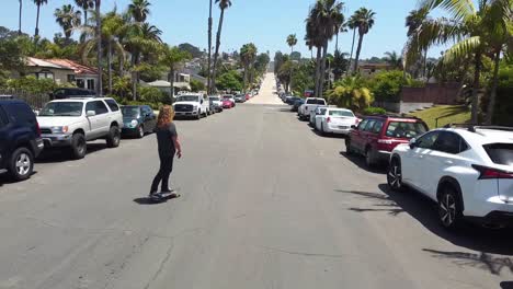 Male-with-long-hair-skating-down-the-street-in-Southern-California-beach-town