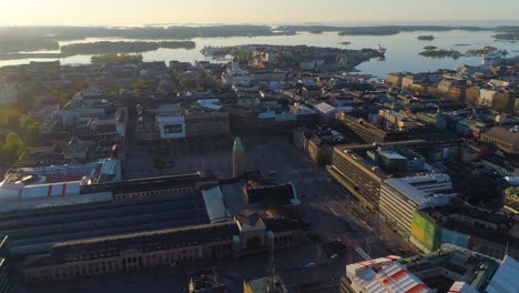 Aerial-view-around-the-Central-Railway-station-on-a-sunny,-summer-morning,-sunrise,-in-Downtown-Helsinki,-Finland--,-orbit,-drone-shot