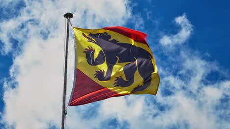 Bern-Canton-flag-waving-on-blue-sky-background,-Switzerland-region-coat-of-arms
