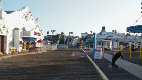 Static-handheld-shot-of-people-walking-along-the-entrance-of-Santa-Monica-pier-in-Los-Angeles-after-reopening-from-Covid-19
