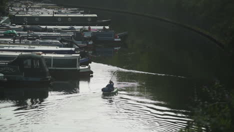 Joven-Haciendo-Kayak-En-El-Canal-Cerca-De-Barcos-Atracados-En-El-Muelle,-Plano-Amplio