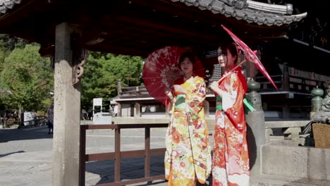Zwei-Wunderschöne-Geisha-Mit-Roten-Kimonos-Und-Regenschirm-Am-Tempel