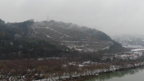 Quiet-mountain-valley-in-fog,-serene-river-in-winter-snowy-scenery-aerial-panorama