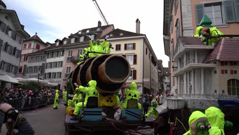 Solothurn,-Suiza---3-De-Marzo-De-2019:-Un-Club-De-Carnaval-Con-Máscaras-Antigás-Y-Trajes-Protectores-Amarillos-Reparte-Dulces-A-Los-Espectadores-Desde-Sus-Enormes-Vehículos