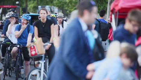 Anonymous-crowd-crossing-the-street-in-front-of-cyclists-waiting-for-their-turn,-slow-motion