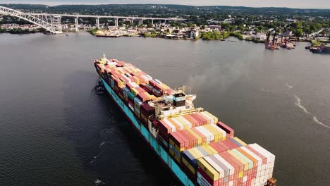 Cargo-ship-being-taxied-by-tug-boats-to-port-near-New-York-City---Aerial-Drone-footage-from-behind