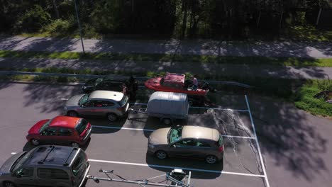 Aerial-view-around-men-working-on-getting-their-boat-on-trailer,-to-the-sea,-at-a-parking-lot---orbit,-drone-shot
