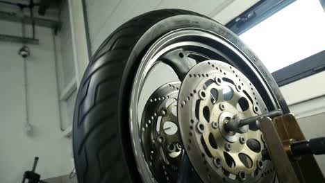 Close-Up-Of-Spinning-Motorbike-Tyre-With-Disc-Brake-Inside-Workshop