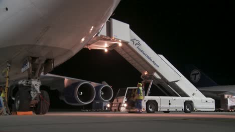 Nighttime-airport-scene-with-cargo-loading-on-an-airplane-via-an-illuminated-airstair