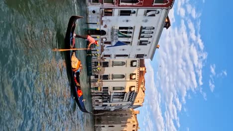 Vertikale-Parallaxenaufnahme-Einer-Gondel-Mit-Touristen,-Die-Ein-Motorboot-In-Venedig-überqueren
