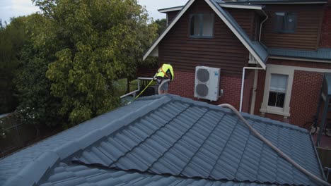 Man-cleaning-roof-gutters-of-house
