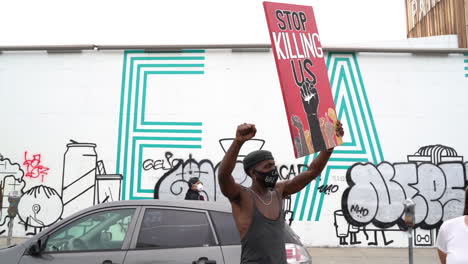 Black-Male-With-Mask-and-Stop-Killing-Us-Sign-During-Black-Lives-Matter-Protest-in-Los-Angeles,-California-USA,-Slow-Motion