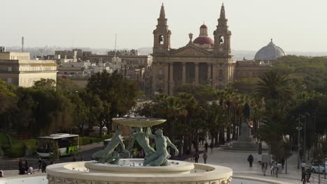 Medium-Shot-Of-The-Triton-Fountain-By-The-City-Gate-Of-Valletta,-Church-Of-Saint-Publius-In-The-Background