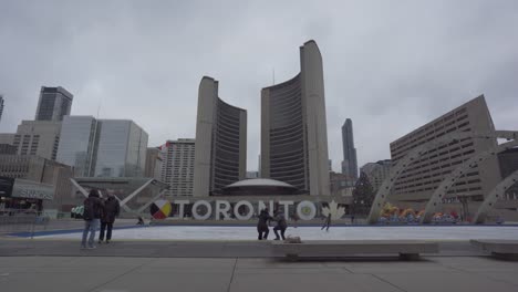 People-taking-selfies-and-walking-by-the-iconic-Toronto-sign-on-Nathan-Phillips-Square-with-City-Hall-in-the-background-on-an-overcast-day