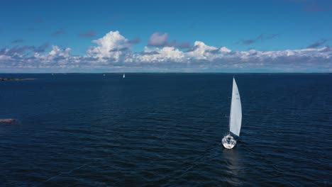 Aerial-view-passing-a-white-sailboat-on-the-high-seas,-at-the-Gulf-of-Finland,-bright,-sunny,-summer-day,-in-Uusimaa,-Finland---low,-dolly,-drone-shot