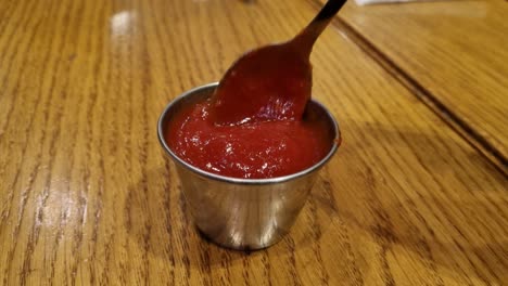 Stirring-Pizza-Sauce-In-A-Stainless-Steel-Bowl-With-A-Silver-Spoon-On-A-Wooden-Table-Top