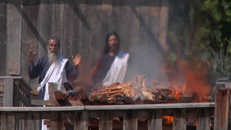 Brennender-Scheiterhaufen-Mit-Zwei-Priestern-Im-Hintergrund-In-Iquitos
