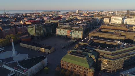 Aerial-view-of-the-Kamppi-shopping-center,-sunny,-summer-morning-sunrise,-in-Helsinki,-Finland--,-tracking,-drone-shot