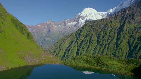 La-Montaña-Annapurna-Se-Refleja-En-El-Lago-Rodeado-De-Vegetación,-Paisaje-De-Nepal,-Disparo-De-Drones-4k