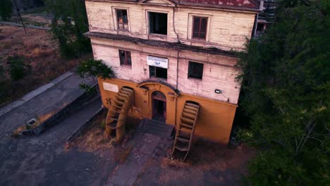 Aerial-view-dolly-out-tilt-up-of-the-laboratory-of-the-ex-maternity-building-forgotten-in-the-Barros-Luco-hospital-in-Santiago-Chile-with-the-sunset-in-the-background---Accordion-shaped-entrance