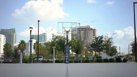 Looking-down-downtown-basketball-court-with-urban-cityscape-skyscrapers-and-cranes-in-business-district-background