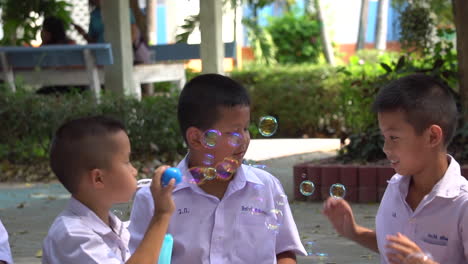 Niños-Tailandeses-Jugando-Con-Burbujas-De-Espuma-En-El-Patio-De-La-Escuela,-Cámara-Lenta,-Bangkok,-Tailandia