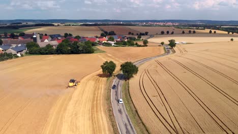 Aerial-Tracking-Shot-of-Car-and-Combine-Harvester-Through-Fields-in-Germany