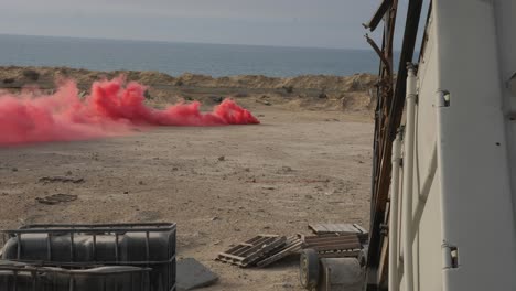 Testing-a-red-smoke-bomb-on-the-beach-in-the-Gaza-Strip,-Palestine