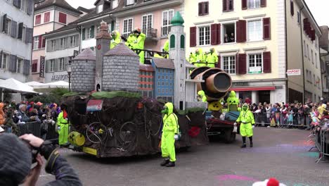 Solothurn,-Suiza---3-De-Marzo-De-2019:-Un-Club-De-Carnaval-Con-Máscaras-Antigás-Y-Trajes-Protectores-Amarillos-Bailando-En-Sus-Enormes-Vehículos