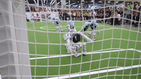 Blick-Hinter-Das-Fußballtornetz-Von-Nao-Robotern,-Die-Fußball-Spielen