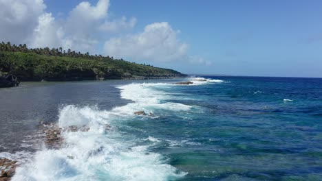 Tonga,-Polynesia,-Oceania,-Drone-Shot-of-Ocean-Waves-Breaking-on-Rocks-by-Coral-Reefs-and-Green-Coastline