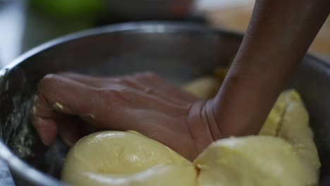 Wet-and-buttery-dough-mix-being-kneaded-by-hand-in-steel-bowl,-filmed-as-closeup-slow-motion-shot