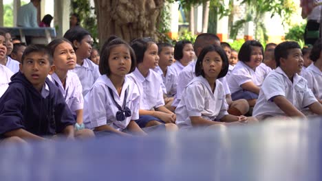 Niños-Tailandeses-Con-Uniformes-Sentados-En-El-Patio-Trasero-De-La-Escuela-Esperando-Clase,-Bangkok,-Tailandia