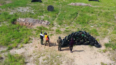 Airsoft-player-team-stand,-discuss-attack-and-defense-strategy-near-tire-pile