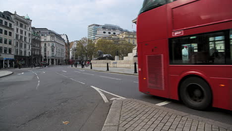 Quiet,-empty-streets-in-London-with-only-one-red-London-bus-in-Coronavirus-Covid-19-pandemic-lockdown-at-Trafalgar-Square-and-Nelsons-Column-in-London-in-the-City-of-Westminster,-England,-UK