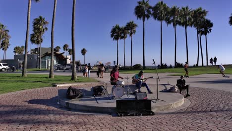 Musicians-play-music-at-Venice-Beach-Boardwalk-on-sunny-day-in-Los-Angeles,-Calfornia---handheld-shot