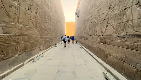 Turistas-Caminando-Entre-Paredes-Llenas-De-Jeroglíficos-Dentro-Del-Templo-De-Horus-En-Edfu,-Egipto