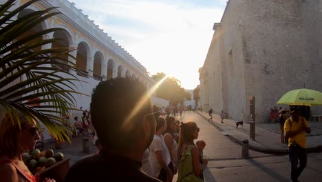 Ein-Mann-Mit-Schwarzem-Hemd-Und-Sonnenbrille-Lauscht-Den-Erklärungen-Eines-Reiseleiters-Mit-Gelbem-Regenschirm-In-Der-Altstadt-Von-Cartagena-De-Indias,-Kolumbien