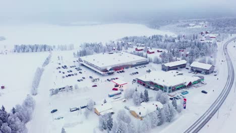 Aerial-view-around-Jounin-kauppa-market,-winter-blizzard,-in-Akaslompolo,-Finland---orbit,-drone-shot