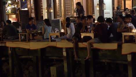 Jóvenes-Tailandeses-Sentados-En-La-Terraza-Del-Restaurante,-Escena-Nocturna.