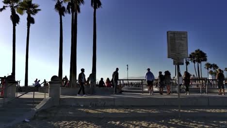 People-standing-around-at-the-Venice-Beach-Skate-Park-with-mountains-in-background,-on-a-sunny-day,-in-Los-Angeles,-California,-USA---handheld-static-shot