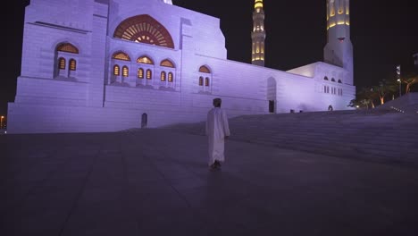 Hombre-Omaní-Caminando-Hacia-Las-Escaleras-Junto-A-La-Gran-Mezquita-Del-Sultán-Qaboos-Por-La-Noche