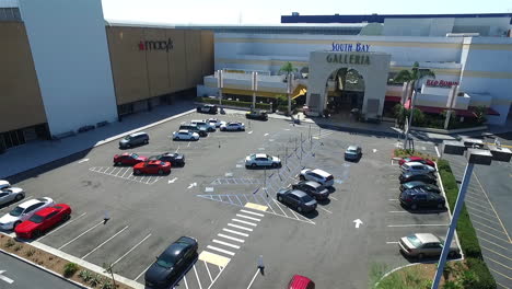 Slow-motion-aerial-drone-flying-back-over-parking-lot-of-South-Bay-Galleria-shopping-mall-by-Hawthorne-Blvd,-and-Artesia-Blvd