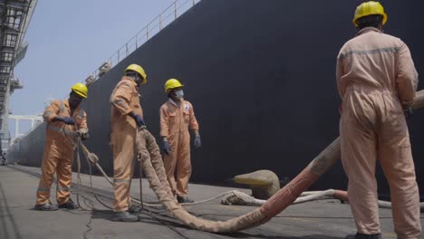 Dockworkers-Holding-And-Untangling-Mooring-Rope-Of-A-Huge-Vessel-At-The-Port